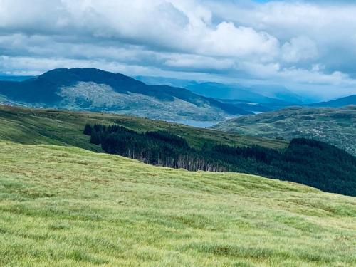 a green grassy hill with mountains in the background at Red Watch Apartment in Oban