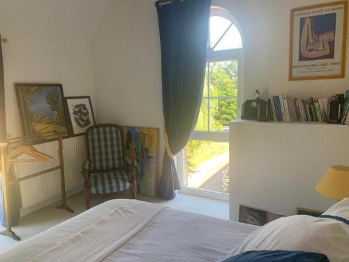 a bedroom with a bed and a window and a chair at La Grange in Saint-Aubin-sur-Scie