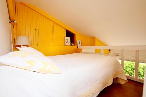 une chambre avec un lit blanc et un mur jaune dans l'établissement Maisonnette au centre de Deauville, à Deauville