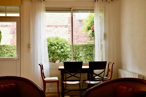 une table et des chaises dans une pièce avec une fenêtre dans l'établissement Maisonnette au centre de Deauville, à Deauville