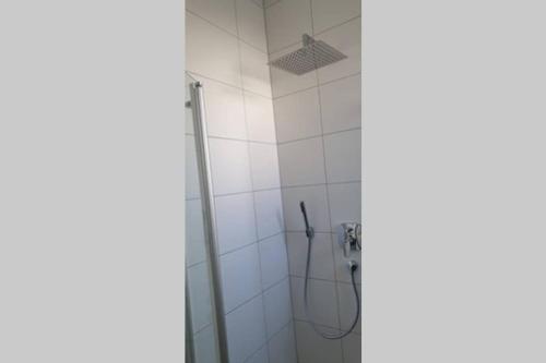e bagno con doccia e parete piastrellata bianca. di Ferienwohnung Charlotte Seebrise a Friedrichshafen