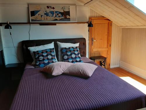 fioletowe łóżko z poduszkami w pokoju w obiekcie appartements d'hôtes La Foulonnerie w mieście Mios