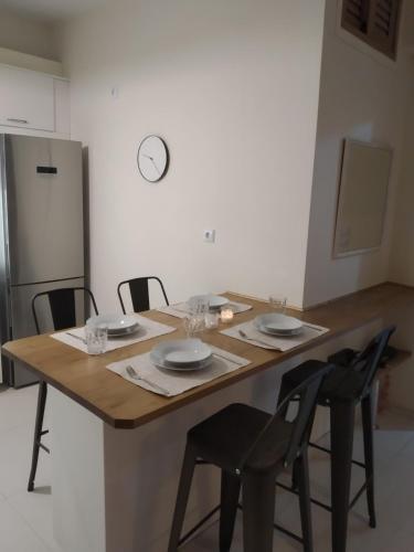a kitchen with a wooden table with chairs and a refrigerator at Thea, Agios Andreas in Néa Koróni