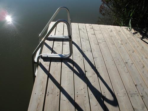 a metal bench sitting on a dock next to the water at Dzeņi in Amatciems