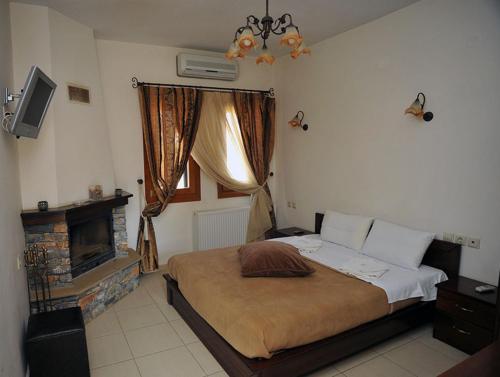 a bedroom with a large bed and a fireplace at Guesthouse Syntrofia in Psarádes