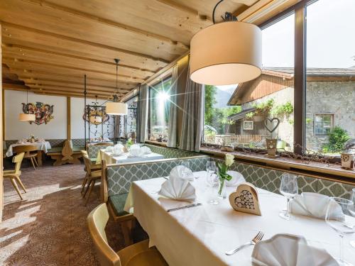 a restaurant with white tables and chairs and windows at Postgasthof Fischerwirt in Walchsee