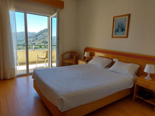 um quarto com uma cama grande e uma varanda em Hotel Miracastro em Castro Laboreiro