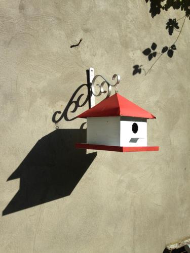 a birdhouse with a red roof hanging on a wall at L'aire des oiseaux in Muno