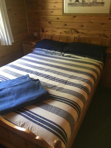 Cama en habitación de madera con toallas azules en Chalet 2, en Tyndrum