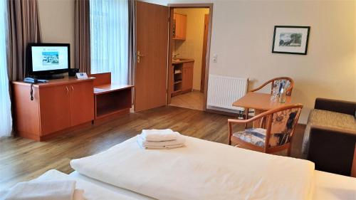 a hotel room with a bed and a table and a television at R&R Villen Baabe in Baabe