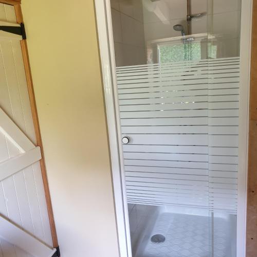 eine Dusche mit weißen Jalousien im Bad in der Unterkunft Gîte de la Founauderie in Roncey