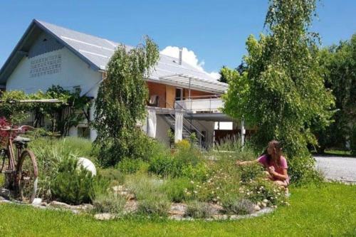 a woman sitting in a garden in front of a house at Hillside Bio Resort Apartment with Mountain View in Prebold