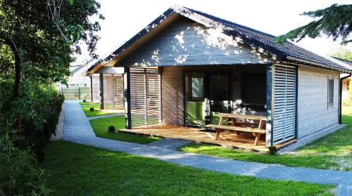 a small cabin with a wooden deck in the grass at luludomki in Mielenko