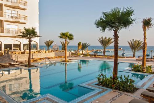 a swimming pool with palm trees in front of a hotel at Royal Star Beach Resort in Hurghada