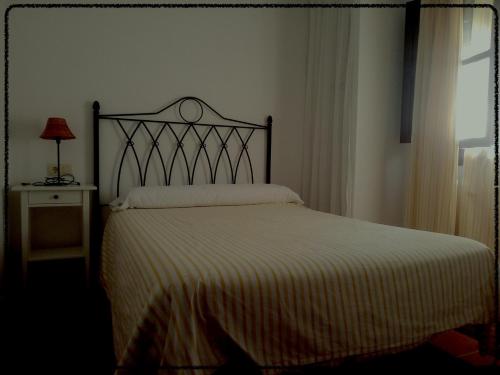 a bedroom with a bed with a white blanket at Apartamento Rural Las Palmeras in Almonaster la Real