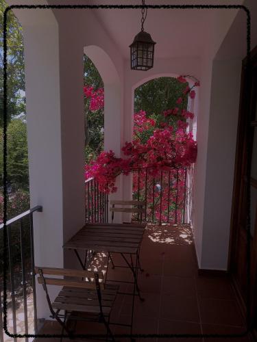 a porch with a bench and a gate with pink flowers at Apartamento Rural Las Palmeras in Almonaster la Real