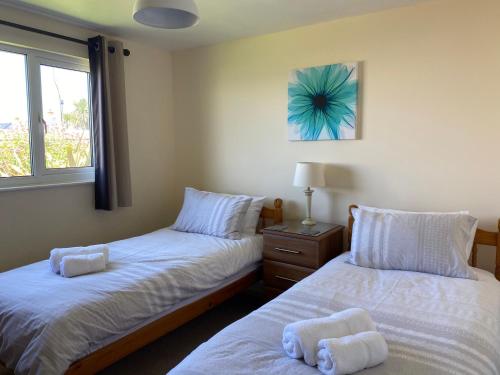 a bedroom with two beds and a window at Copthorne - Tintagel in Tintagel