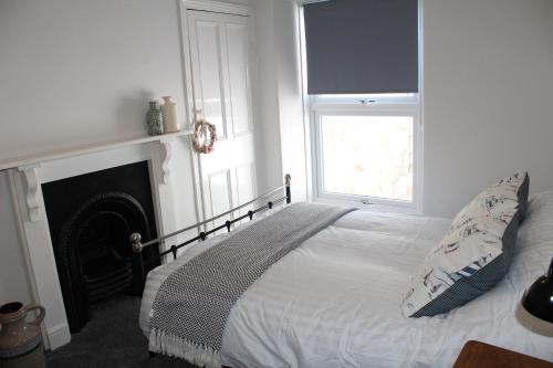 a bedroom with a bed with a fireplace and a window at Karensa in Newlyn
