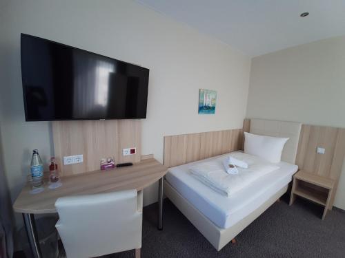 a room with a bed and a desk with a flat screen tv at Hotel Siebenschläfer am Wasserturm in Alsdorf