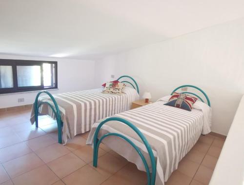 2 łóżka w pokoju z białymi ścianami w obiekcie Domenique w mieście Budoni