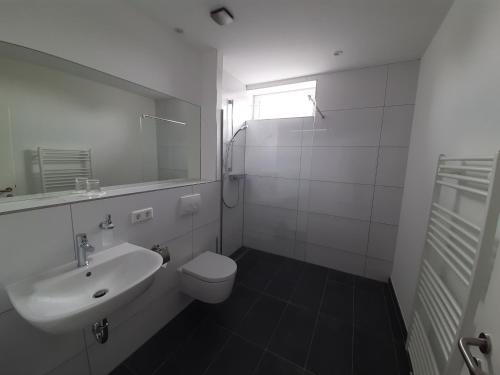 a white bathroom with a sink and a toilet at Hotel Siebenschläfer am Wasserturm in Alsdorf
