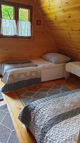 アウグストゥフにあるDomek Letniskowy Nad Jezioremのログキャビン内のベッドルーム1室(ベッド2台付)