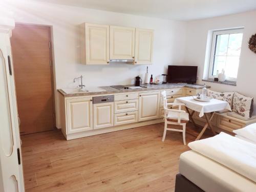 a kitchen with white cabinets and a table and a table at Landidyll am Thiersee in Thiersee