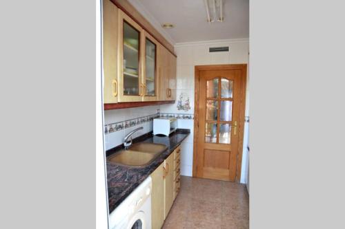a kitchen with wooden cabinets and a sink at APARTAMENTOS GALLACH (LA ERMITA) in Chulilla
