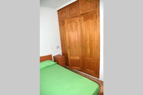 a small bedroom with a green bed and wooden cabinets at APARTAMENTOS GALLACH (LA ERMITA) in Chulilla