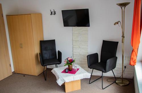 sala de estar con 2 sillas y mesa con TV en Ausflugsrestaurant & Pension Aalbude & Hausfloßvermietung am Kummerower See, en Dargun