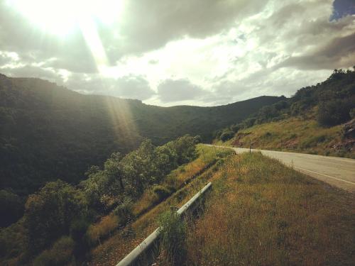 a road in the middle of a mountain with the sun at Casa de Pimenteis in Vimioso