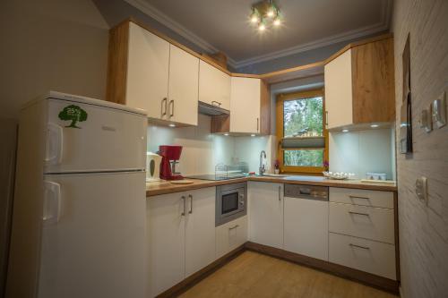 uma cozinha com armários brancos e um frigorífico branco em Kirowy Domek em Kościelisko