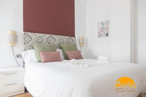 ein Schlafzimmer mit einem großen weißen Bett mit rosa Kissen in der Unterkunft Apartamento Caleta - FREE PARKING by Cadiz Time in Cádiz