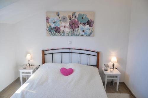 a white bed with a pink heart on it at Apartmani Carnizza in Ražanac