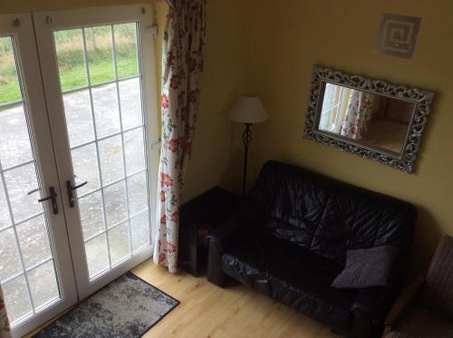 a living room with a leather couch and a mirror at Rathgillen Mews in Nobber