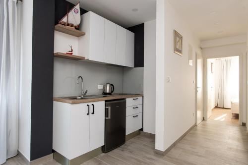 a kitchen with white cabinets and a black refrigerator at Exclusive Villa Almissa with swimming pool and sea view in Lokva Rogoznica
