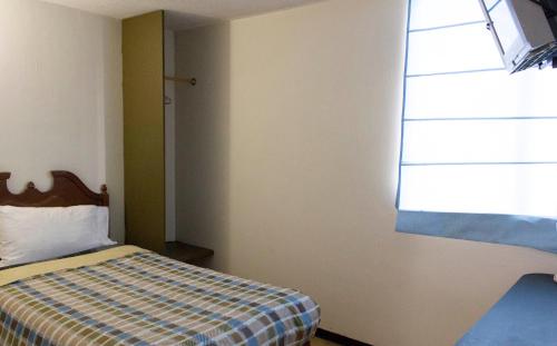 a bedroom with a bed with a checkered blanket and a window at Departamento 7/7 in Tlaxcala de Xicohténcatl