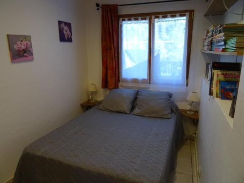 een kleine slaapkamer met een bed en een raam bij La vigne sous les pins in Castagniers
