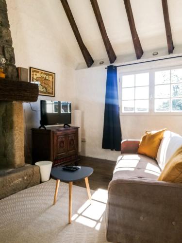 un salon avec un canapé et une télévision dans l'établissement Ti Baou, à Châteauneuf-du-Faou