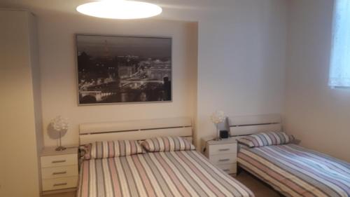 a bedroom with two beds and a picture on the wall at Appartamento Perla del Lago - Enchanting Lake View in Malcesine