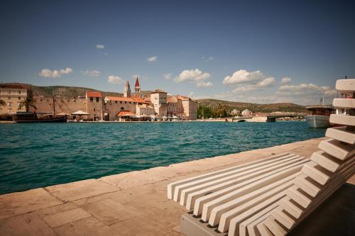 a chaise lounges on a dock in a body of water at Villa Kudelik - Stone Story in Trogir