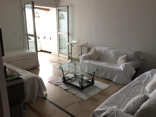a living room with a couch and a glass table at Belaire host appartment in Boumhel El Bassatine