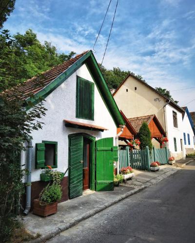 una casa blanca con persianas verdes en una calle en Zebegényi Présház, en Zebegény
