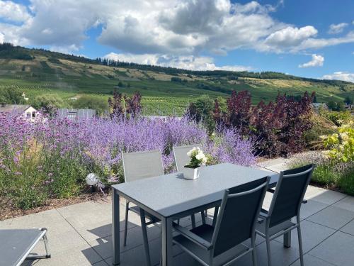 a table and chairs on a patio with purple flowers at Ferienwohnung Weinbergblick in Mehring