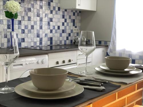 a kitchen counter with two plates and wine glasses at Casa La Mimbrera in Las Navas del Marqués