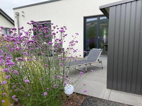 a garden with purple flowers and a chair on a patio at Ferienwohnung Weinbergblick in Mehring