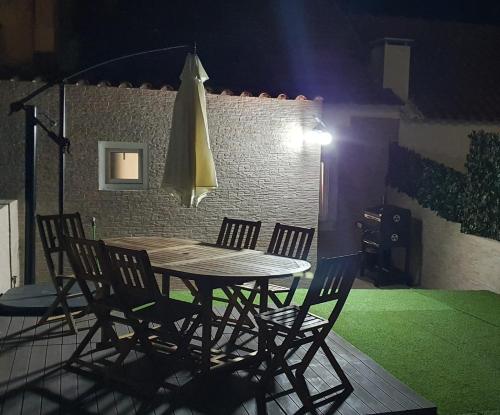 a table with chairs and a umbrella in a room at Vila Azul in Sesimbra