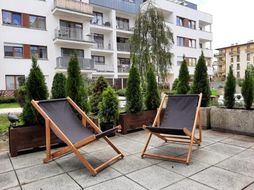 2 Stühle auf einer Terrasse vor einem Gebäude in der Unterkunft Platan 3 in Świnoujście