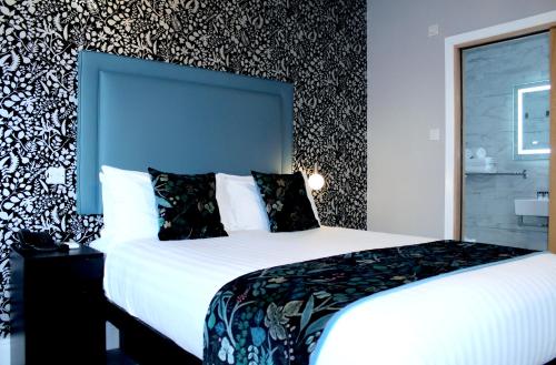 a bedroom with a large white bed with a blue headboard at NOX Paddington in London