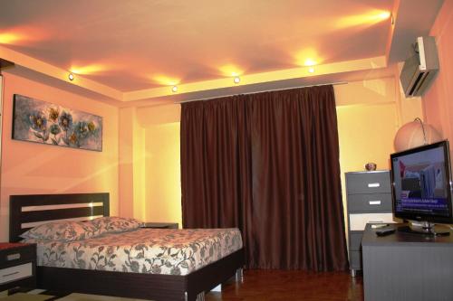 a hotel room with a bed and a television and a television at City center Deluxe apartment in Bucharest